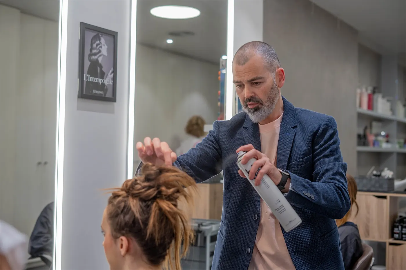 David Suquet fixant un recollit amb laca davant del mirall